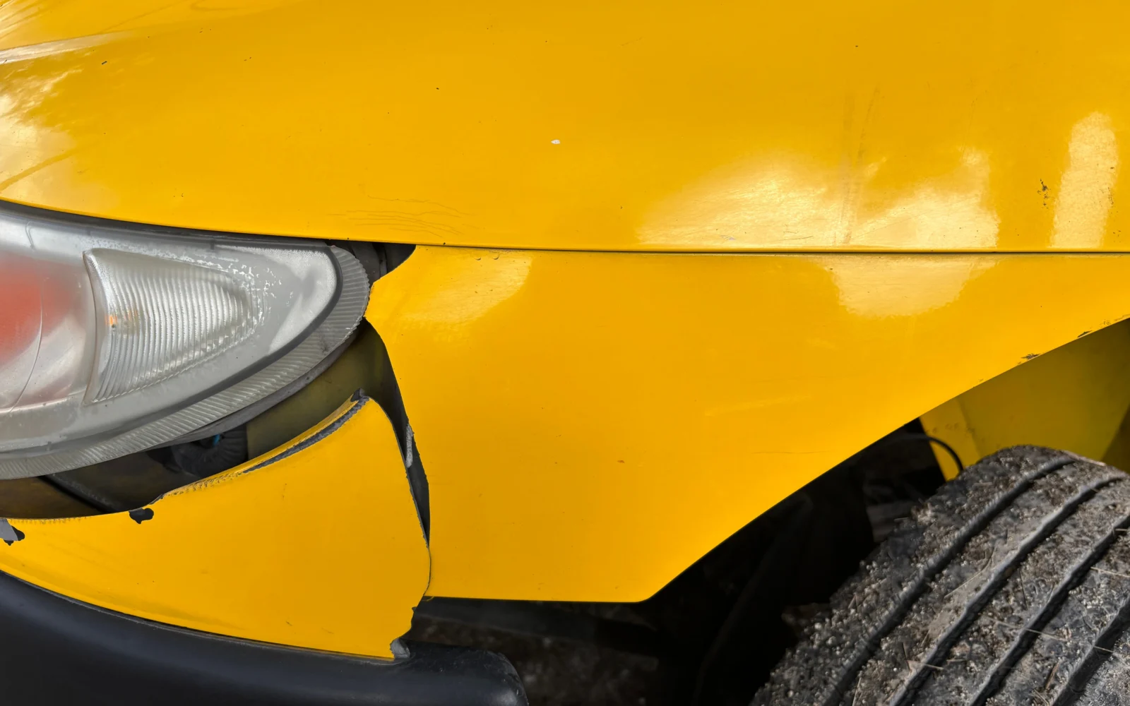 Poškodený predný nárazník žltého automobilu